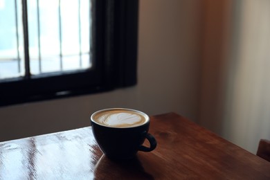Photo of Cup of aromatic coffee on wooden table in cafe