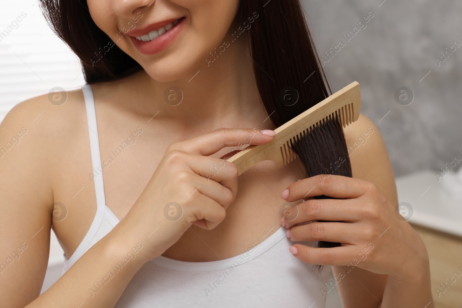 Photo of Woman brushing her hair indoors, closeup view