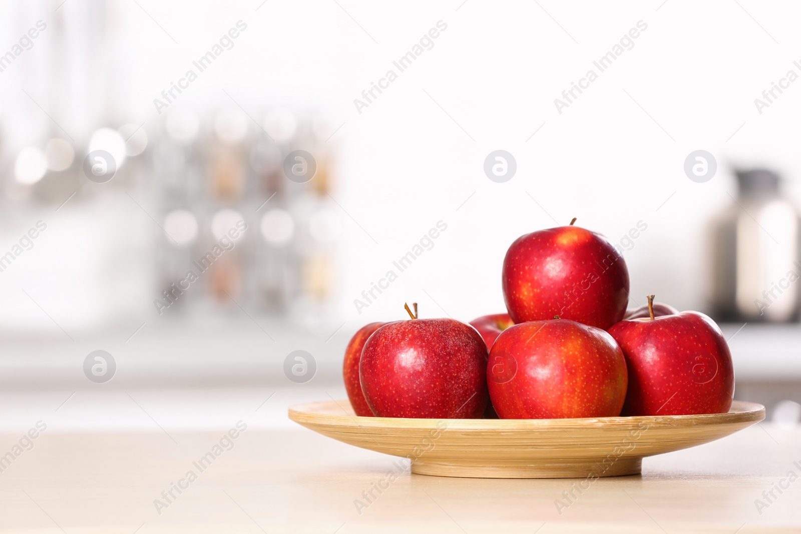 Photo of Plate with sweet red apples on table in kitchen, space for text