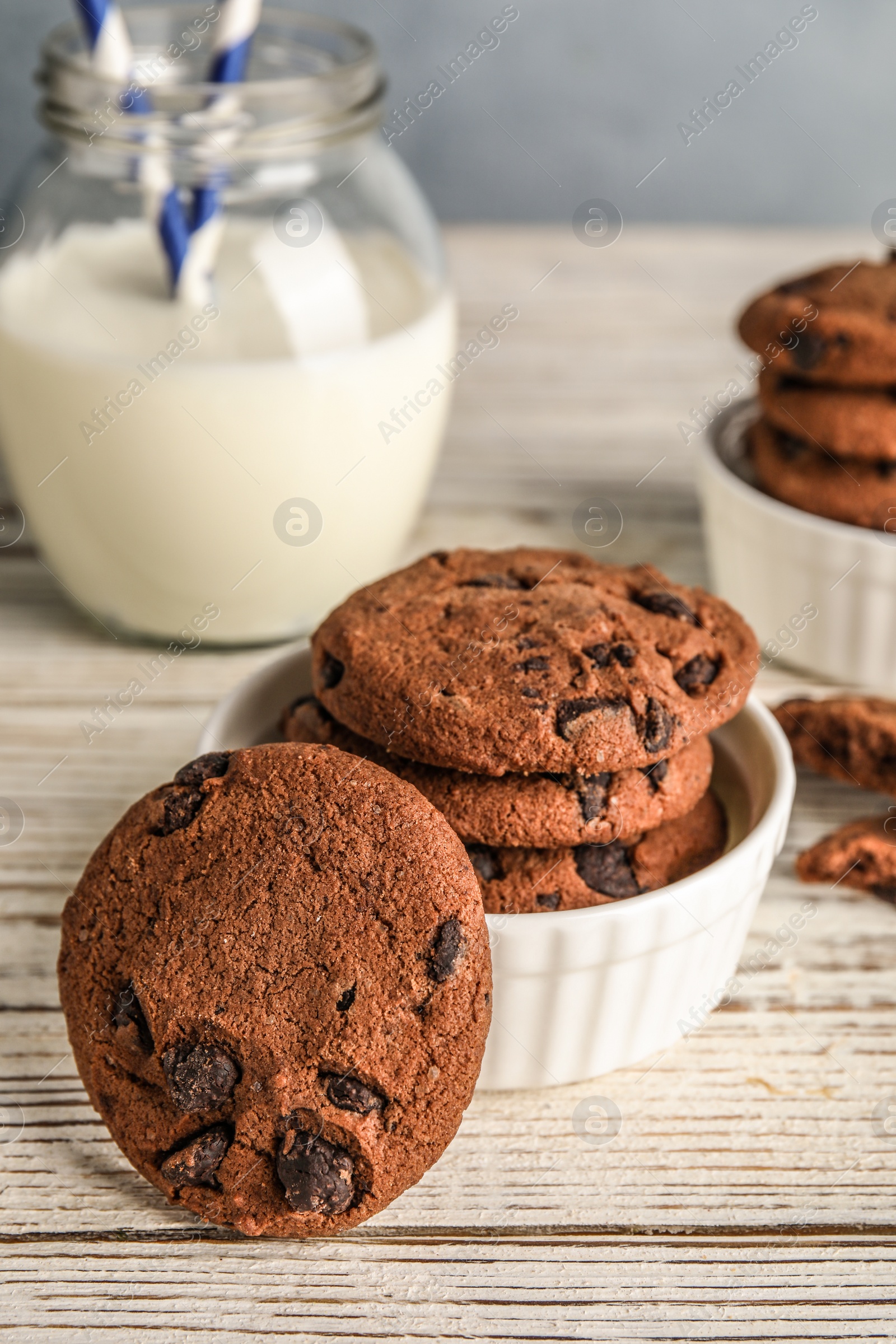 Photo of Bowl with tasty chocolate chip cookies on wooden table