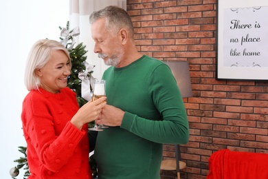 Photo of Mature couple with glasses of champagne at home. Christmas celebration