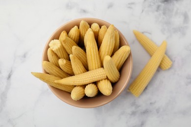 Photo of Bowl and pickled baby corn on white marble table, flat lay