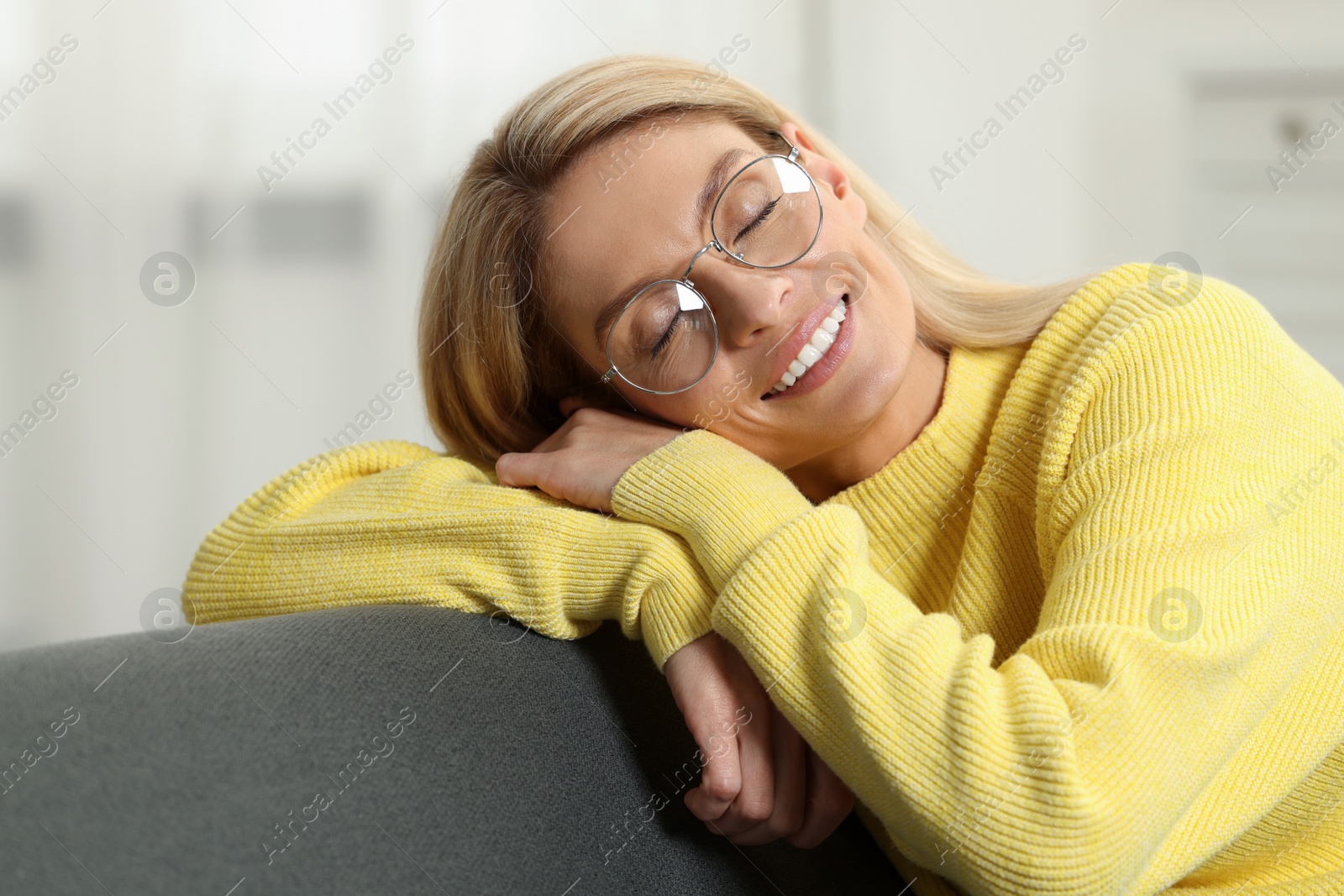 Photo of Happy woman in stylish glasses on sofa indoors