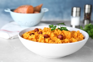 Photo of Bowl of tasty sweet potato puree on grey table