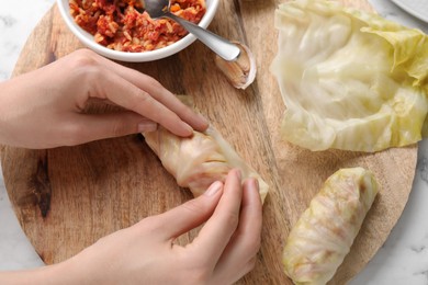 Photo of Woman preparing stuffed cabbage roll at table, top view