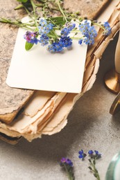 Photo of Beautiful Forget-me-not flowers and antique book on grey table, closeup