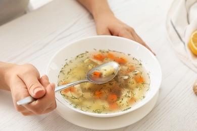 Photo of Sick woman eating fresh homemade soup to cure flu at table, closeup