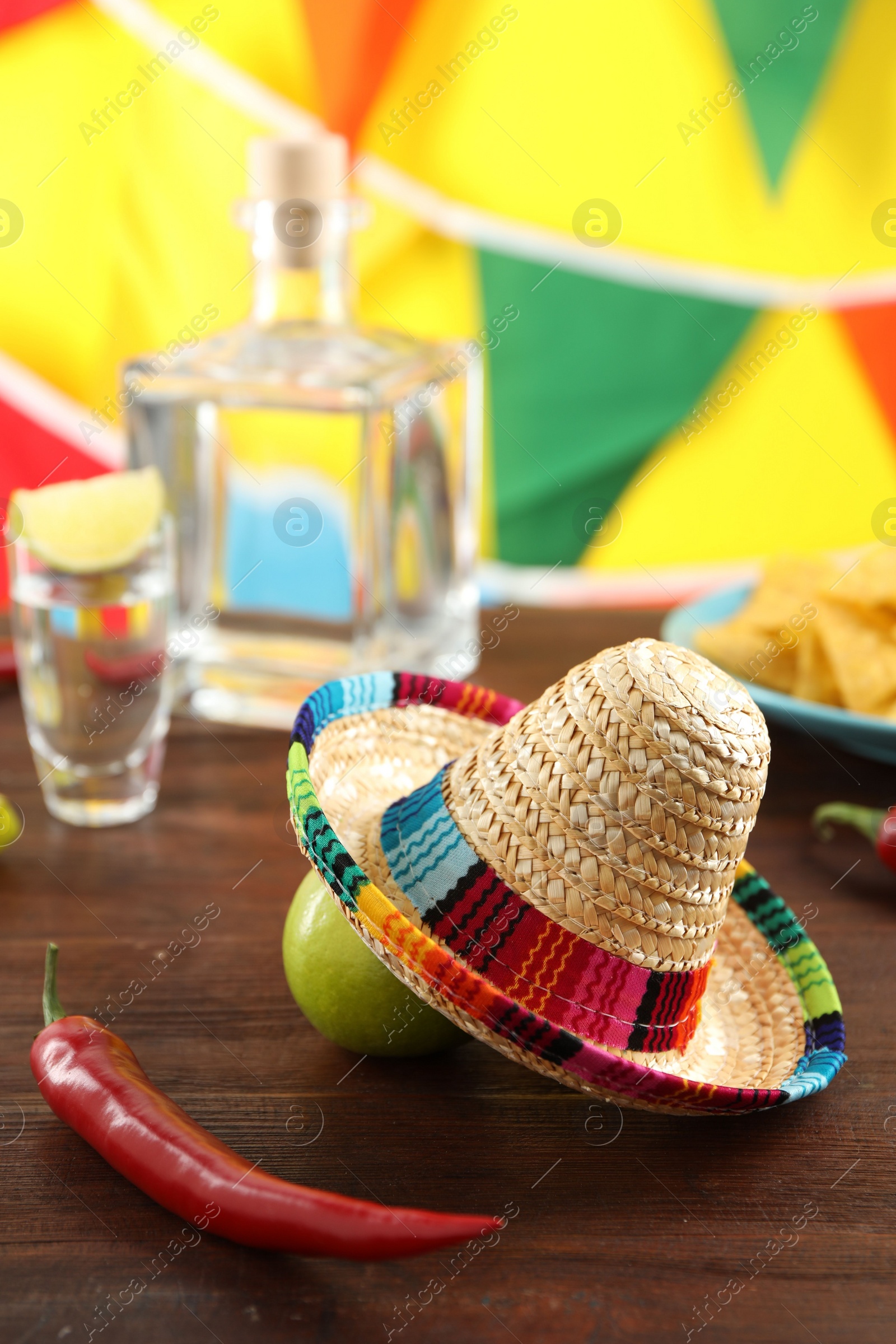 Photo of Mexican sombrero hat, lime and chili pepper on wooden table