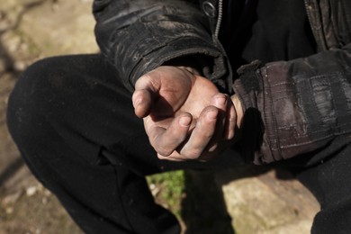 Photo of Poor homeless man with dirty hands outdoors, closeup