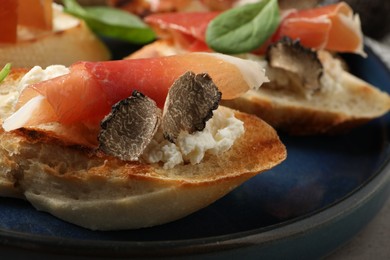 Photo of Delicious bruschetta with cheese, prosciutto and slices of black truffle on plate, closeup