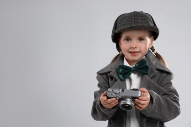 Cute little detective with vintage camera on grey background. Space for text