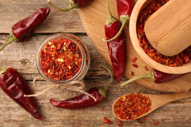 Photo of Chili pepper flakes and pods on wooden table, flat lay