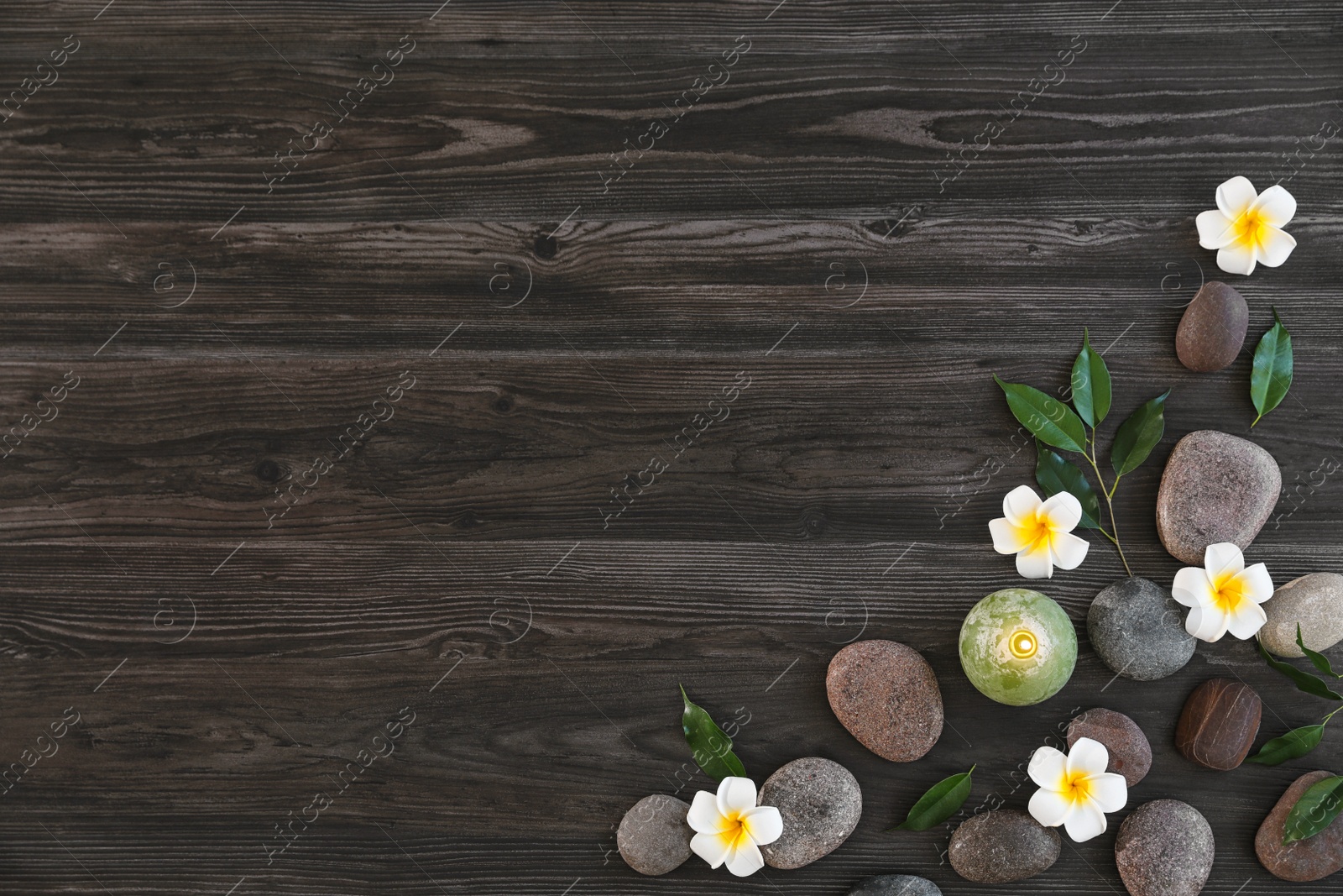 Photo of Flat lay composition with spa stones, flowers and candle on wooden background. Space for text