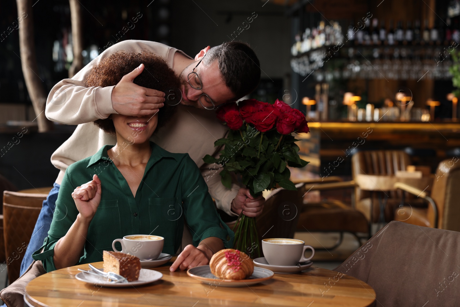 Photo of International dating. Handsome man presenting roses to his girlfriend in restaurant, space for text