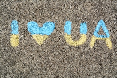Photo of Inscription I love Ukraine drawn by blue and yellow chalk on asphalt, top view