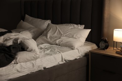 Photo of Nightlight and alarm clock on bedside table near bed indoors