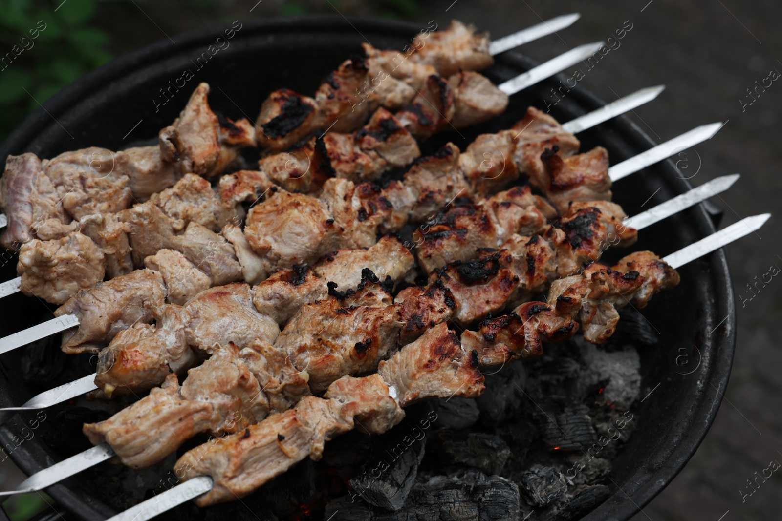 Photo of Cooking delicious kebab on metal brazier outdoors