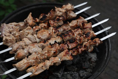 Photo of Cooking delicious kebab on metal brazier outdoors