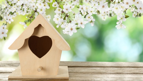 Beautiful bird house on wooden table outdoors, space for text