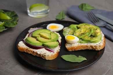 Tasty avocado toasts served on grey table