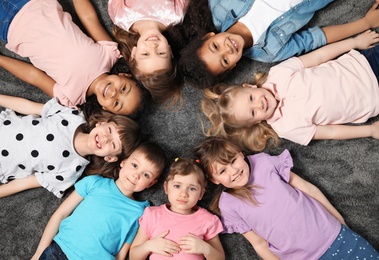 Adorable little children lying on floor together indoors, top view. Kindergarten playtime activities