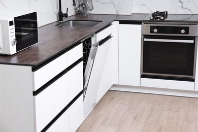 Photo of Built-in dishwasher with open door in kitchen