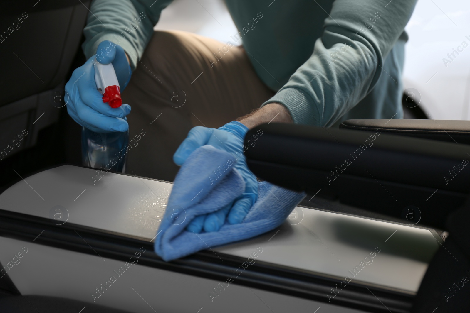 Photo of Man in gloves cleaning car with disinfectant spray and rag, closeup. Preventive measure during coronavirus pandemic