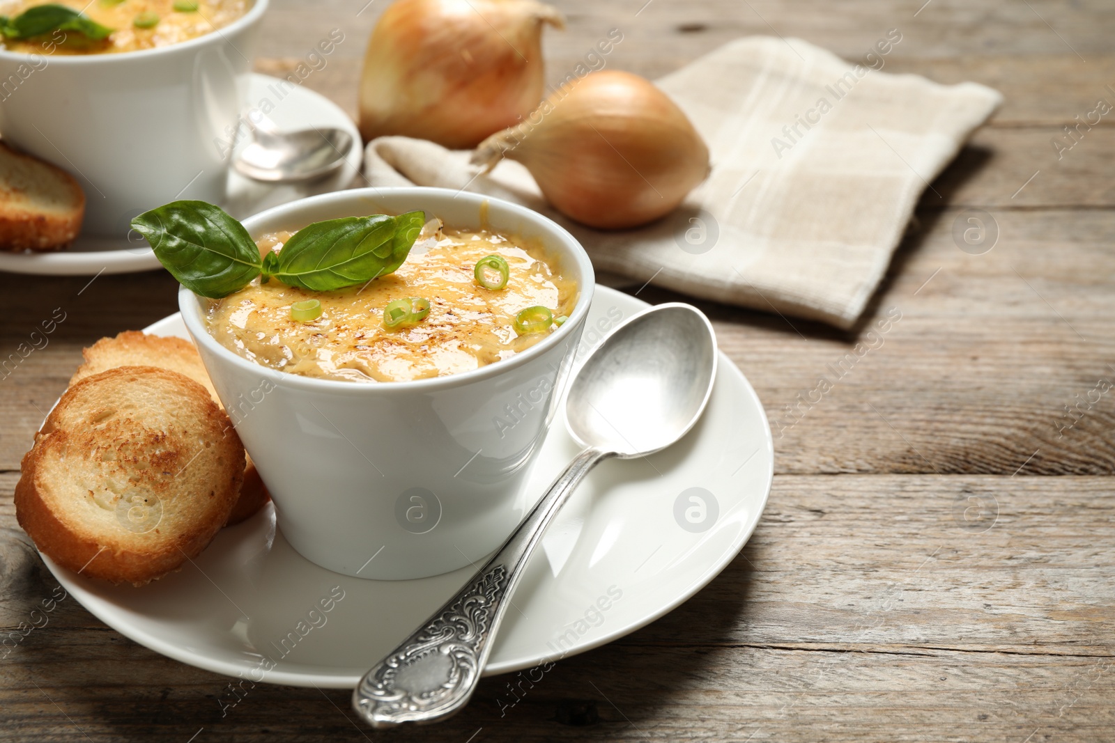 Photo of Tasty homemade french onion soup served on wooden table. Space for text