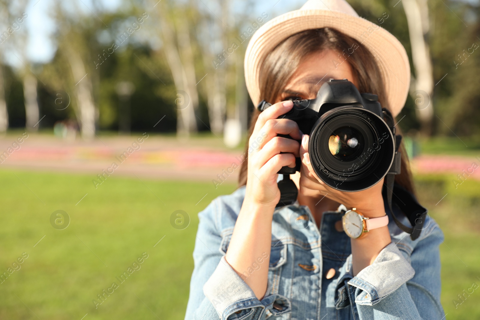 Photo of Young female photographer taking photo with professional camera on street. Space for text