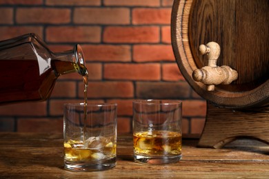 Photo of Pouring whiskey from bottle into glass on wooden table