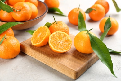 Fresh tangerines with green leaves on light table