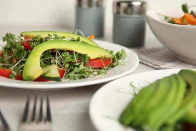 Delicious vegetable salad with avocado and microgreen served on light table