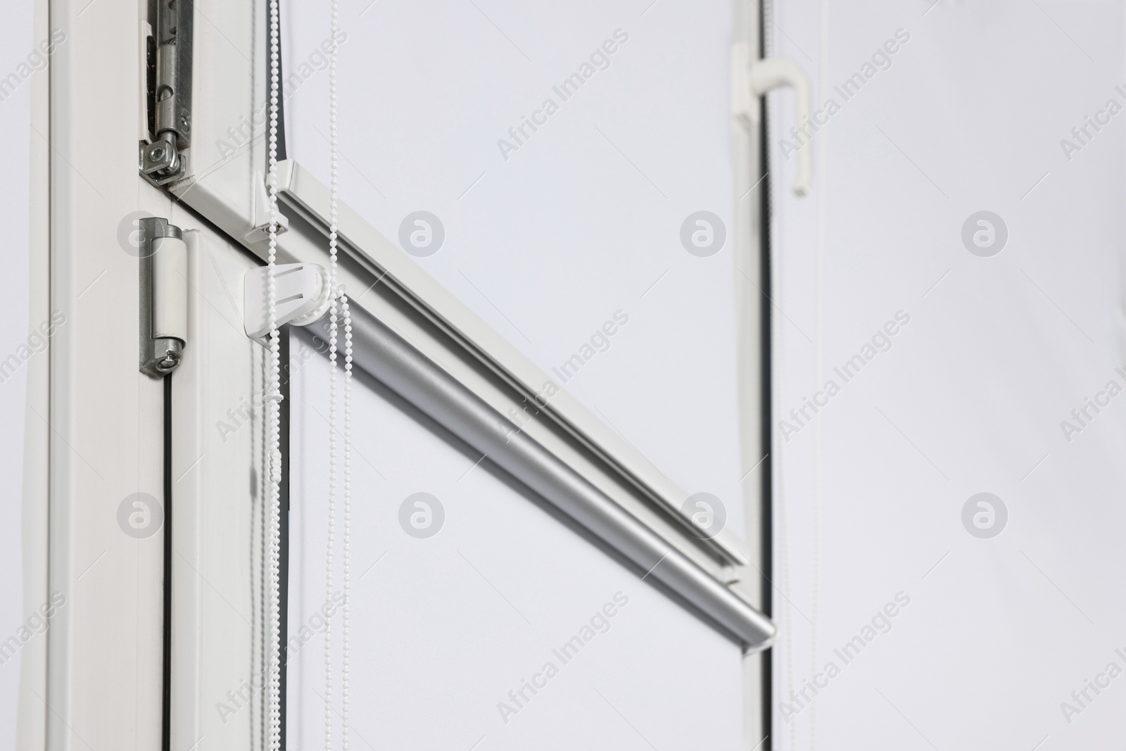 Photo of Window with closed white roller blinds indoors, low angle view