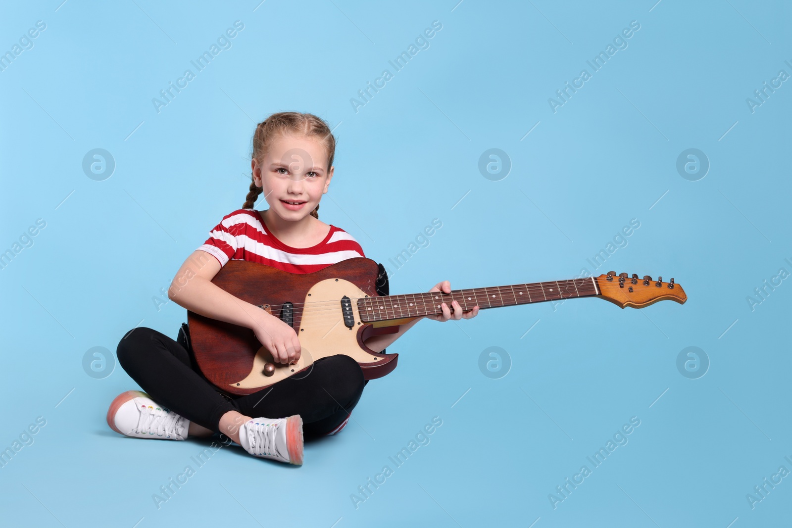 Photo of Cute girl with electric guitar on light blue background