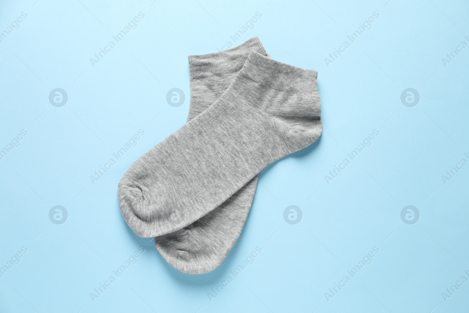 Photo of Pair of grey socks on light blue background, flat lay