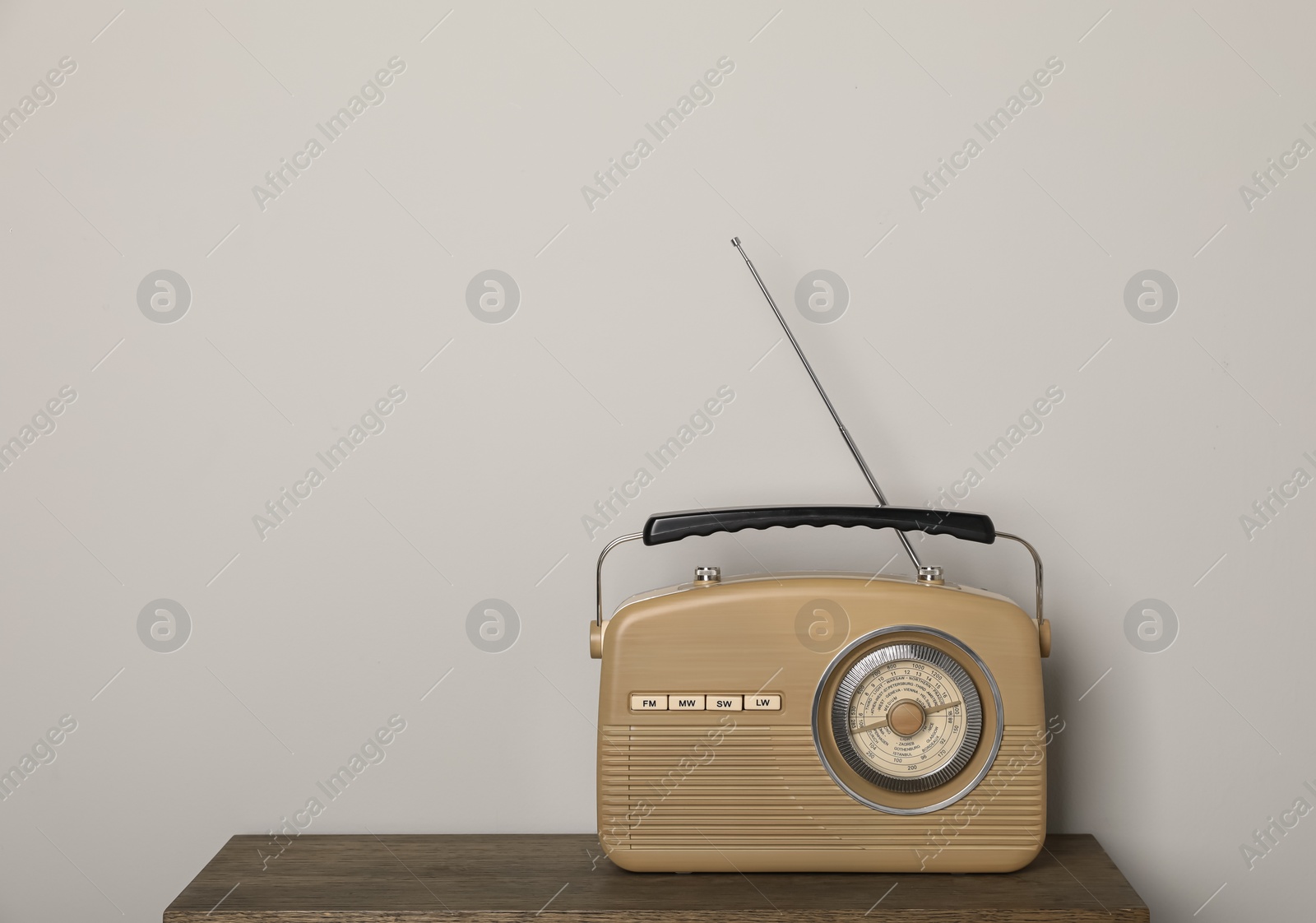 Photo of Retro radio receiver on wooden table against light grey background. Space for text