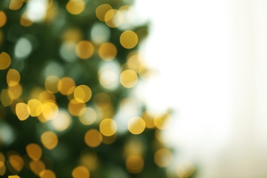 Photo of Blurred view of fir tree with glowing Christmas lights indoors. Festive mood