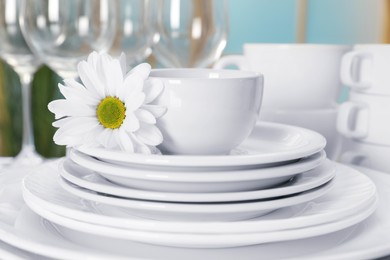 Photo of Set of clean dishware and flower on table, closeup