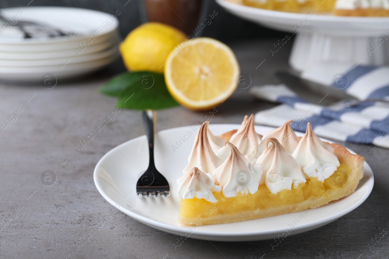 Photo of Piece of delicious lemon meringue pie served on grey table. Space for text