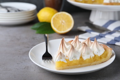 Photo of Piece of delicious lemon meringue pie served on grey table. Space for text
