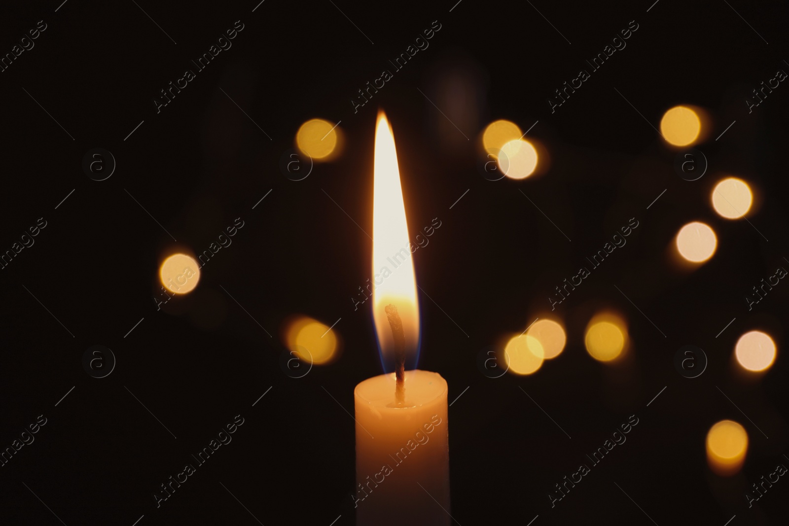 Photo of Wax candle burning on blurred background, closeup