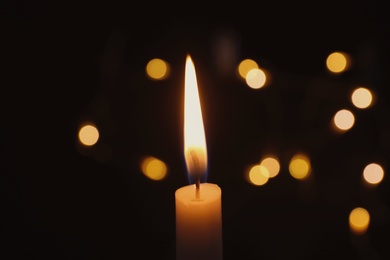 Photo of Wax candle burning on blurred background, closeup