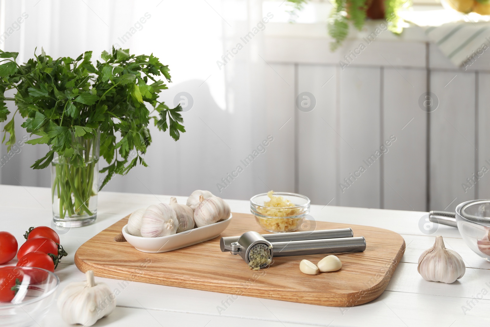 Photo of Garlic press and products on wooden table in kitchen