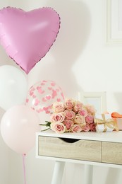 Beautiful bouquet of roses, gifts and balloons on white table. Happy birthday greetings