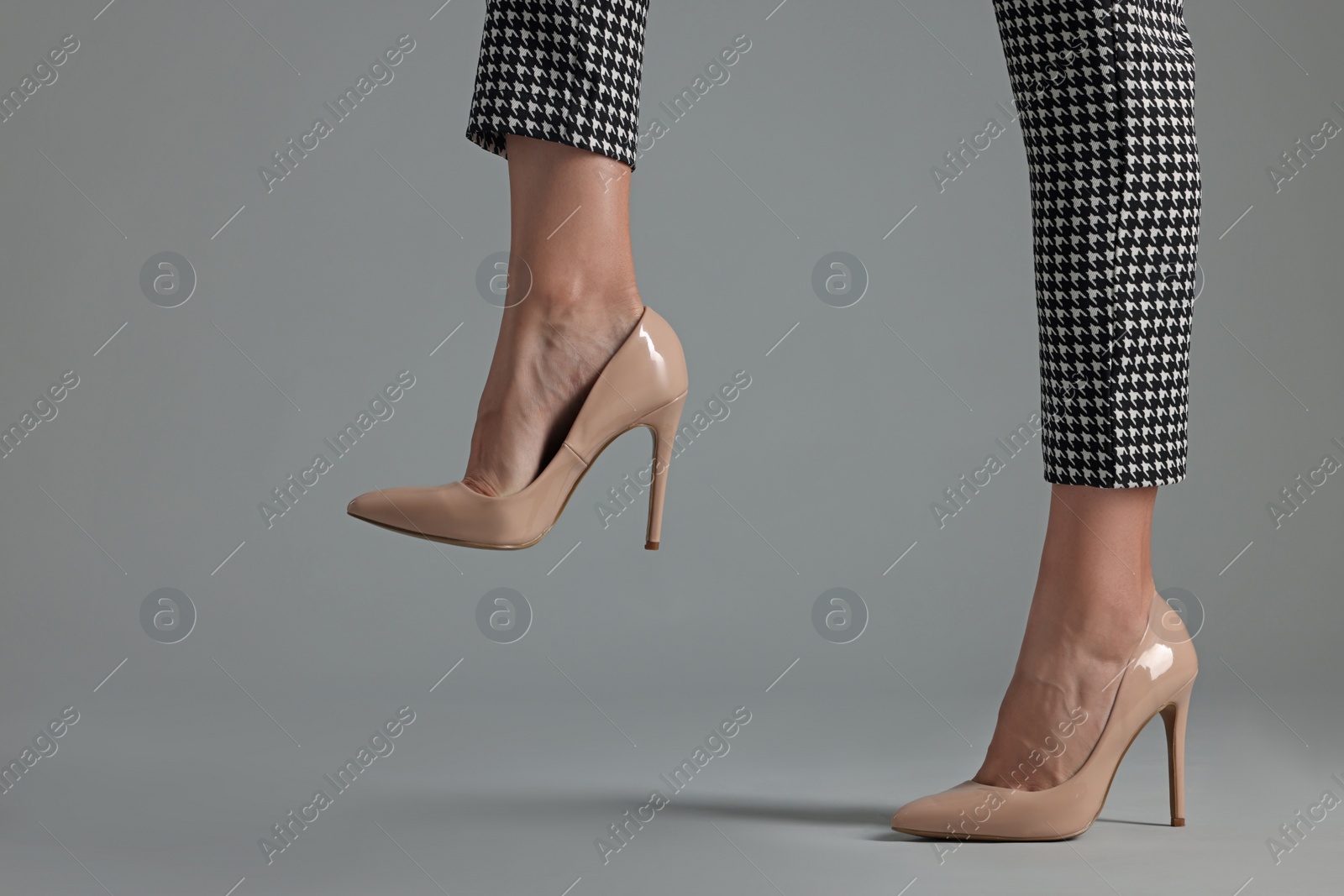 Photo of Businesswoman in beige shoes on grey background, closeup