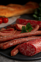 Photo of Different tasty sausages on grey table, closeup