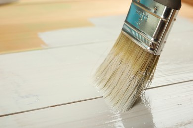 Photo of Applying white paint onto wooden surface, closeup. Space for text