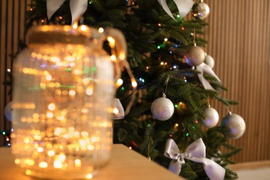 Photo of Christmas tree with stylish decor and fairy lights indoors