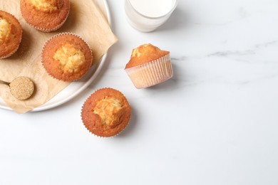 Photo of Delicious sweet muffins, glass of milk and brown sugar on white marble table, flat lay. Space for text