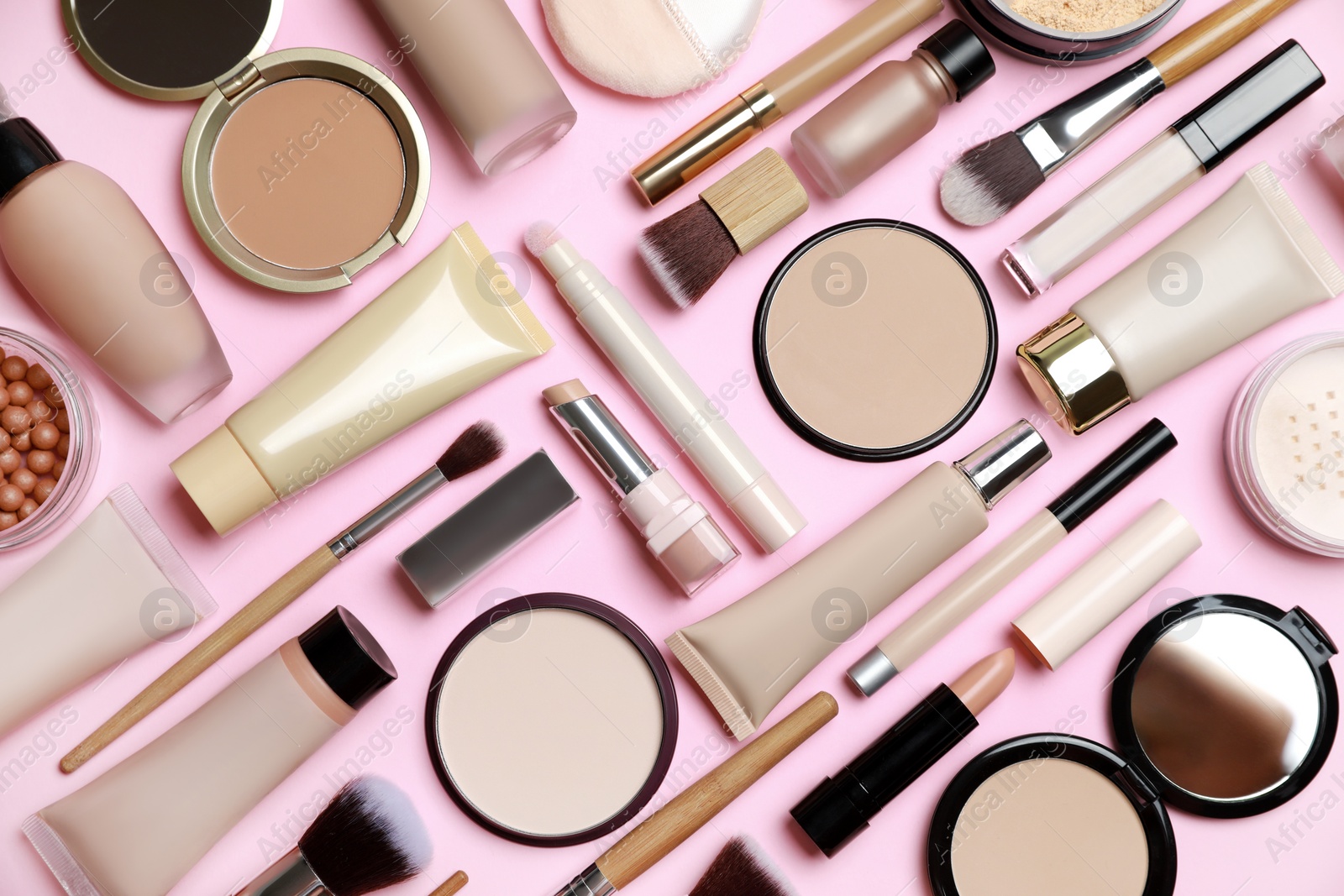 Photo of Face powders and other decorative cosmetic products on pink background, flat lay